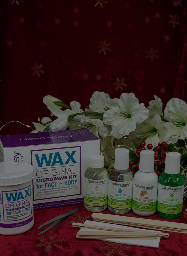 Wax kit for face and body with bottles and tools on a red surface with festive background.